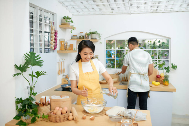 "Pareja cocina panadería en cocina habitación, joven asiático hombre y mujer juntos haciendo pastel y pan con huevo
," - Foto, imagen