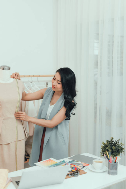 "junge asiatische Modedesignerin misst Schaufensterpuppe in ihrem Atelier" - Foto, Bild