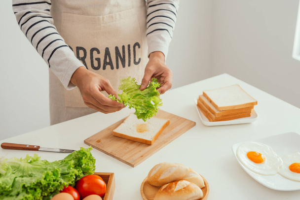 mannelijke handen bereiden een open broodje met groenten - Foto, afbeelding