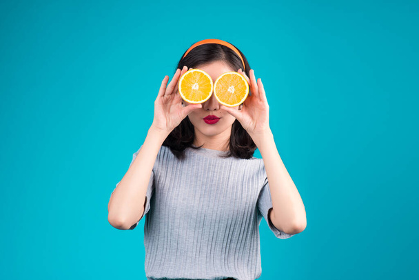 Healthy food. Smiling lovely pinup asian girl holding orange over blue background. - Photo, Image
