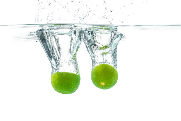 Fresh lime dropped into the water with water splash on a white background - Photo, Image