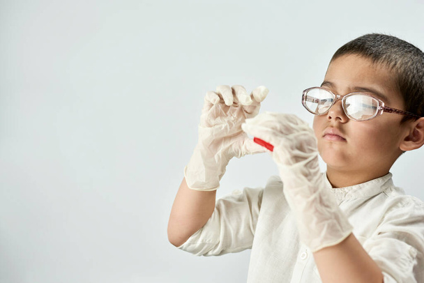 "Gözlüklü ve eldivenli bir çocuk plastikle oynuyor." - Fotoğraf, Görsel