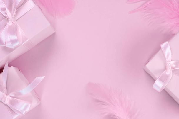 Hintergrund mit rosa Geschenkschachteln mit rosa Schleifen auf rosa Hintergrund mit Federn dekoriert, Draufsicht, das Konzept der Feier eines Mädchens Geburtstag, Party, Jubiläum in rosa, Verkauf und Einkauf oder neugeborenes Mädchen. Hochwertiges Foto - Foto, Bild