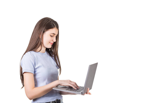 白い背景に隔離された会話の中でメッセージを入力し、彼女の手にノートパソコンを保持する若い女性の側のビュー。 - 写真・画像