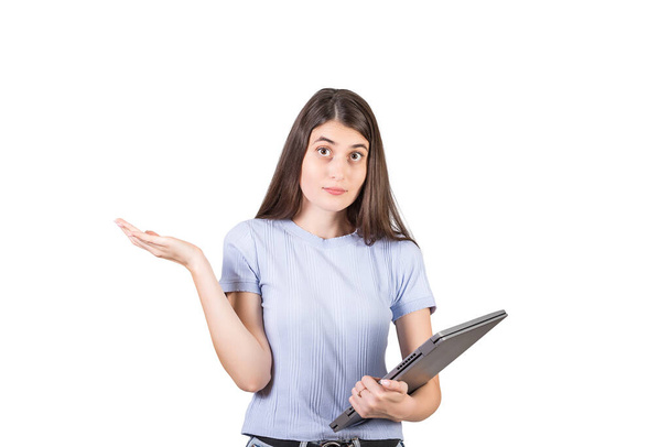 Perplexed young woman shrugging shoulders as holds a defect laptop in her hand, looking confused to camera isolated on white background - Fotoğraf, Görsel