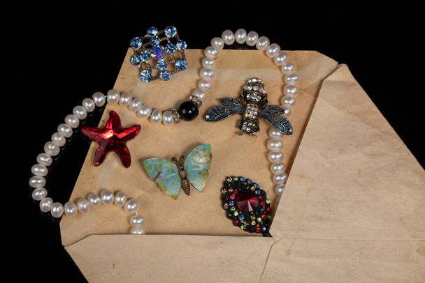 Mücevherler, broşlar, boncuklar eski bir mektup zarfından döküldü.. - Fotoğraf, Görsel