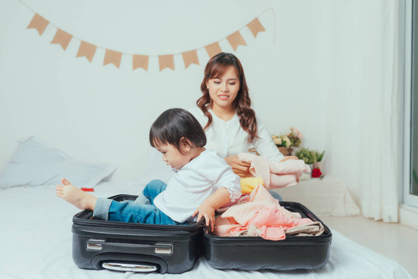 Mom and daughter are packing suitcases for the trip. - 写真・画像