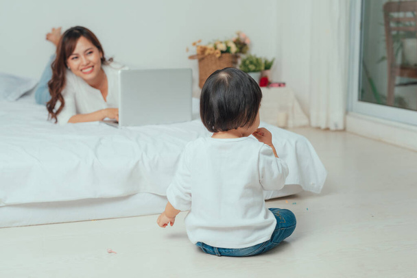 "mother with laptop and her child on the bed in the morning" - Photo, image