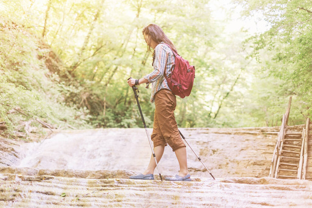 "Hiker woman crossing a river with trekking poles." - Foto, Imagem