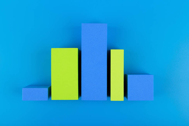 "Geschäftsdiagramm oder Leistungsdiagramm mit blauen und grünen Balken mit dynamischem Aufstieg und Fall vor blauem Hintergrund" - Foto, Bild