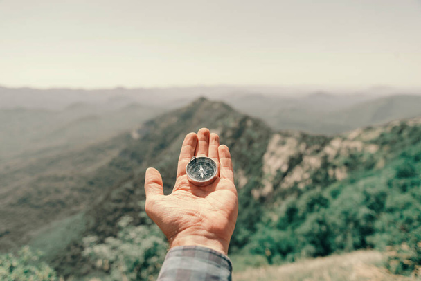 "Compass on palm male hand high in summer mountains, pov." - Foto, afbeelding