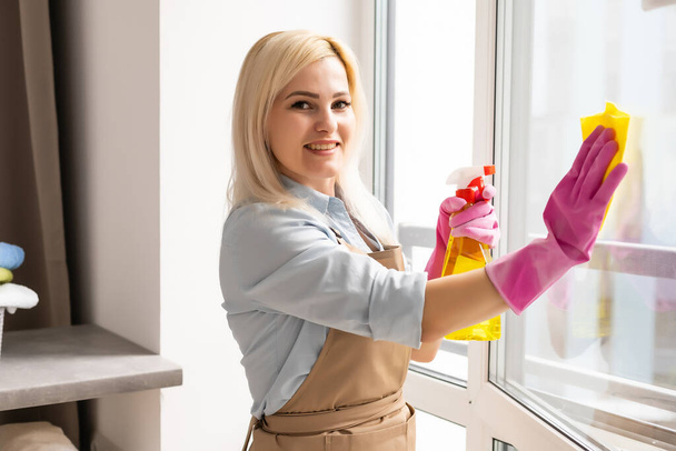 mujer joven lava una ventana en el apartamento - Foto, imagen
