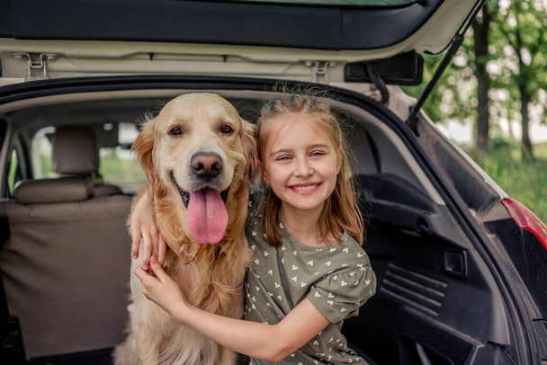 Preteen κορίτσι με το σκυλί golden retriever στο αυτοκίνητο - Φωτογραφία, εικόνα
