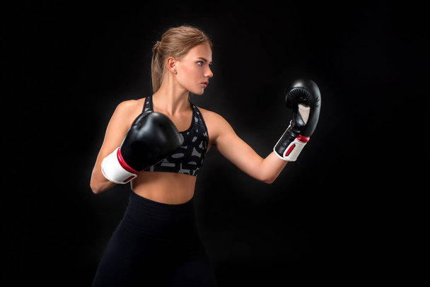 Bella atleta donna in guanti da boxe, in studio su sfondo nero
.  - Foto, immagini
