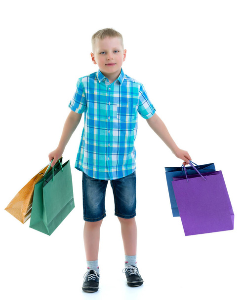 Little boy waving multicolored paper bags. He goes shopping - Fotoğraf, Görsel