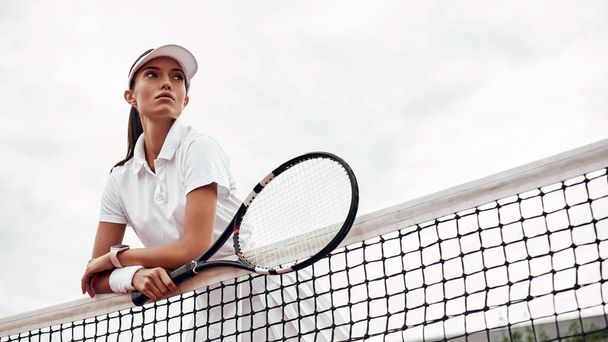 "Young tennis player standing on a court and holding a racket." - Foto, afbeelding