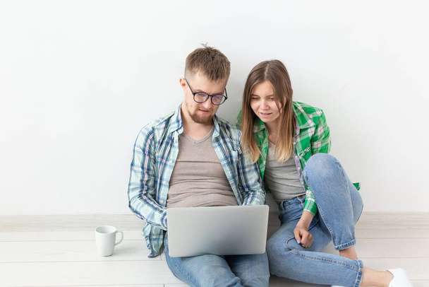 Okouzlující mladý pár v příležitostném oblečení hledajícího interiérový Návrhář pro svůj nový Apartmán s využitím notebooku a vysokorychlostního internetu. Koncepce designu bytu. - Fotografie, Obrázek