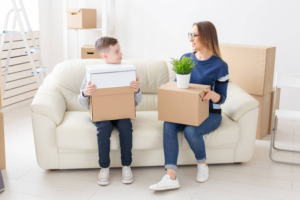 Cute mom and little boy son sort boxes with things after the move. The concept of housewarming mortgage and the joy of new housing. - Photo, Image