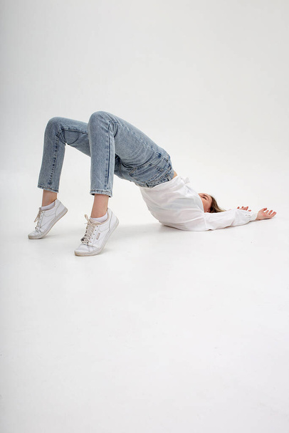 young caucasian girl lying on floor, lifting her body, stretching on cyclorama - Photo, Image