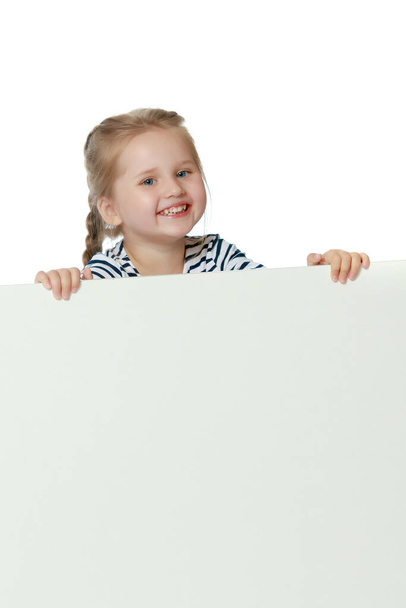 Una bambina sta guardando da dietro uno striscione vuoto. - Foto, immagini