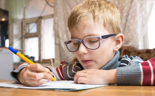 Сосредоточенный первоклассник учится писать и делать домашнее задание - Фото, изображение