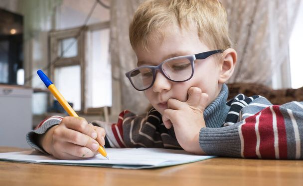 "Сосредоточенный первоклассник учится писать и делать домашнее задание" - Фото, изображение