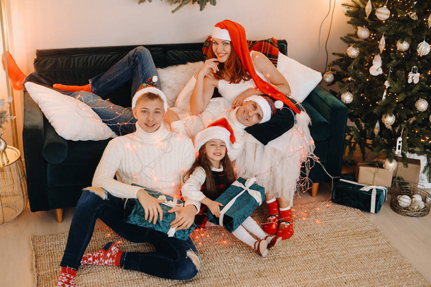 Close-up portrait of a happy family sitting on a sofa near a Christmas tree celebrating a holiday - Photo, Image