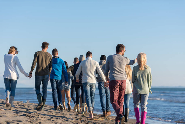 Ομάδα φίλων τρέχει στην παραλία κατά τη διάρκεια της ημέρας του φθινοπώρου - Φωτογραφία, εικόνα