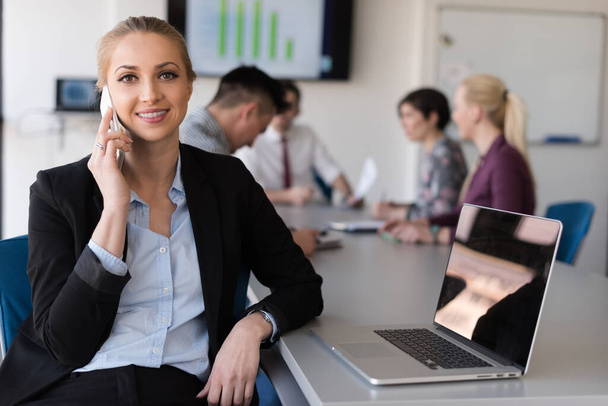 "деловая женщина говорит по телефону в офисе с командой на заднем плане" - Фото, изображение
