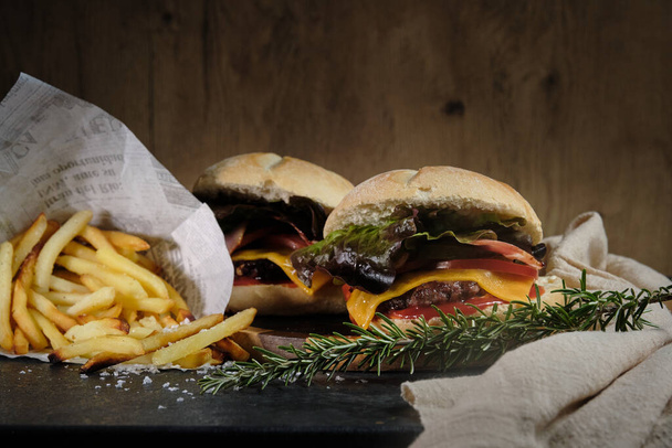 hamburgers en frietjes op een donkere achtergrond - Foto, afbeelding
