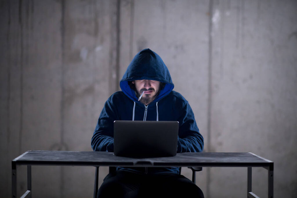 young hacker using laptop computer while working in dark office - Photo, Image
