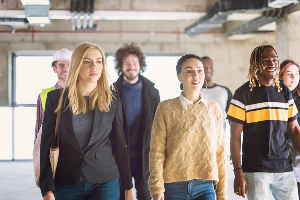 junge multiethnische Geschäftsleute gehen durch unfertiges Startup-Büro - Foto, Bild