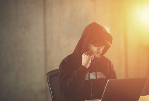 giovane hacker di talento che utilizza il computer portatile mentre lavora in ufficio buio - Foto, immagini