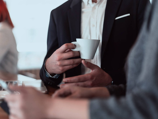 macro photo of a businessman in a cafe in a suit holding a cup of coffee. - Photo, Image