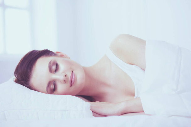 Νεαρή όμορφη γυναίκα ξαπλωμένη στο κρεβάτι. - Φωτογραφία, εικόνα