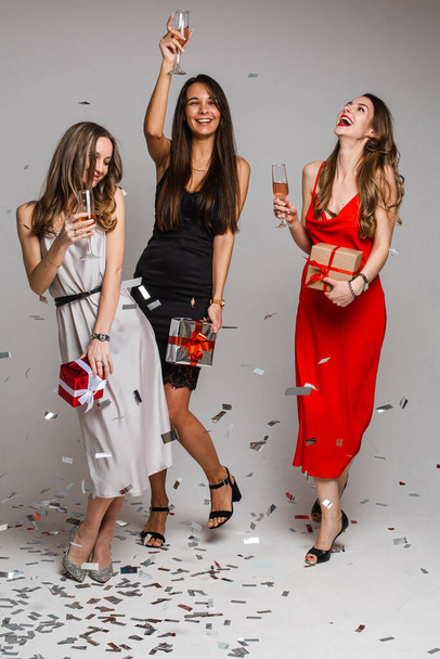 "Cheerful three female friends with gift boxes dancing" - Photo, Image
