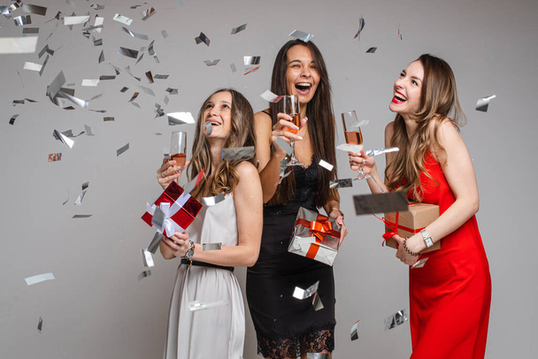 three cheerful friends in beautiful dresses celebrate new year with glasses of wine - Foto, Bild