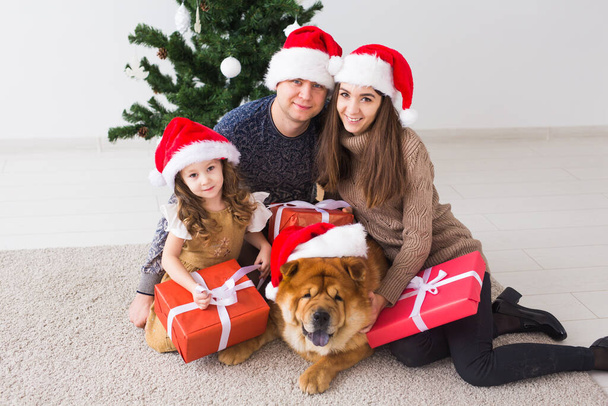 Κατοικίδια ζώα, γιορτές και εορταστική έννοια - Οικογένεια με το σκυλί βρίσκονται στο πάτωμα κοντά στο χριστουγεννιάτικο δέντρο. - Φωτογραφία, εικόνα