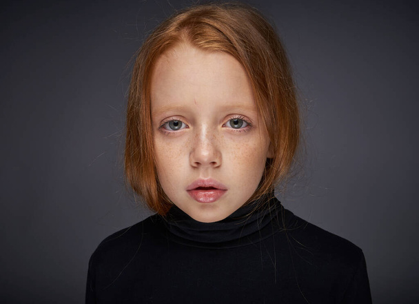 menina ruiva com sardas em seu rosto em uma camisola preta posando - Foto, Imagem