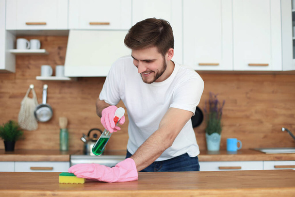 Single handsome man cleaning kitchen at home. - Foto, Imagem