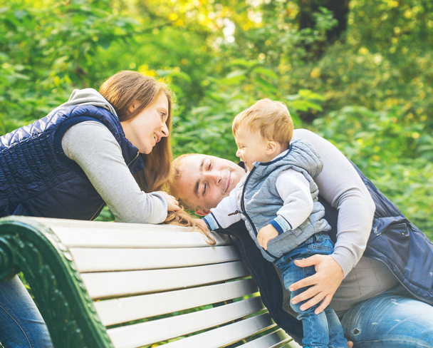 Family sitting on wooden bench - Photo, image