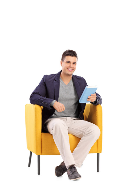 Man holding book in armchair - Zdjęcie, obraz