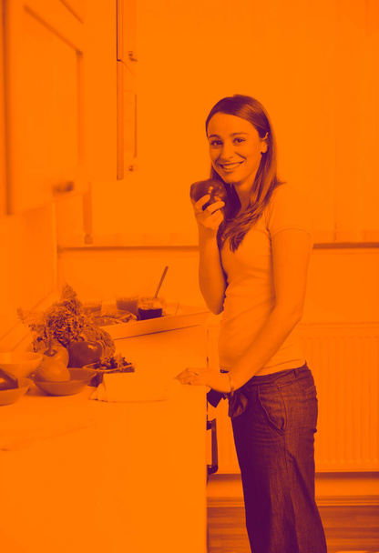 happy young  woman with apple in kitchen - Photo, Image