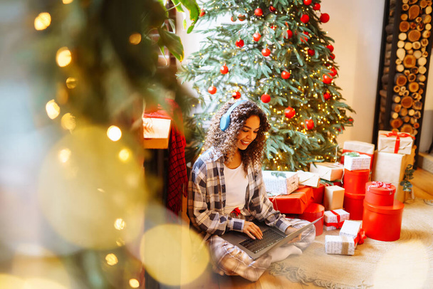 Young  woman having video call  by christmas tree at home. Christmas online holiday.  - Photo, image