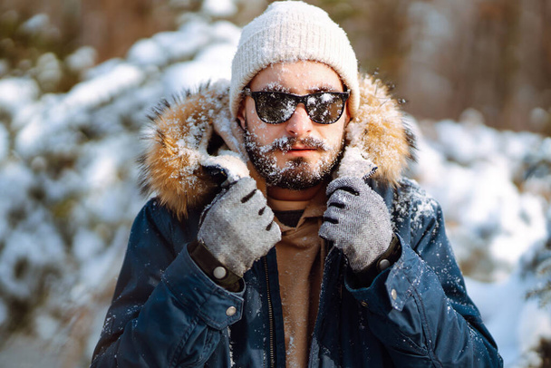 Bearded man smiling at camera in winter park. Season, christmas, travel and people concept. - 写真・画像