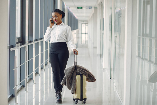 "Чорна жінка з валізою в аеропорту
" - Фото, зображення