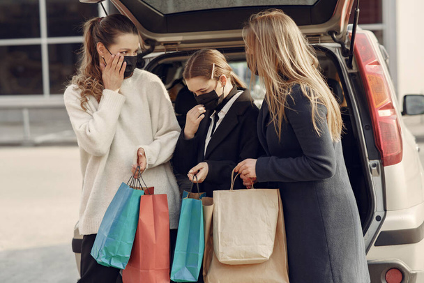 Maskeli kadınlar ellerinde alışveriş çantalarıyla dışarı çıkıyorlar. - Fotoğraf, Görsel