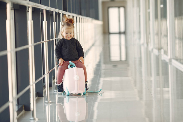 Klein meisje met een koffer op het vliegveld - Foto, afbeelding