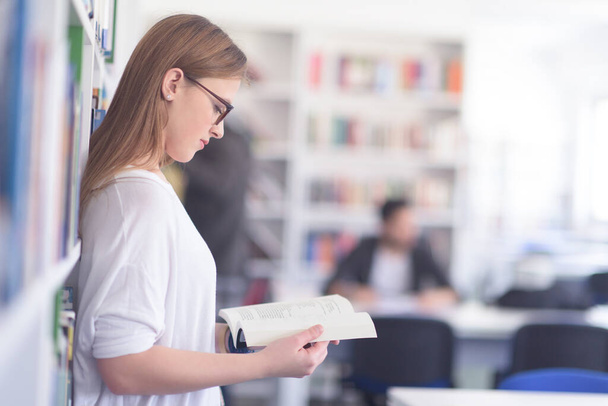 portrait of female student reading book in library - Foto, Imagem