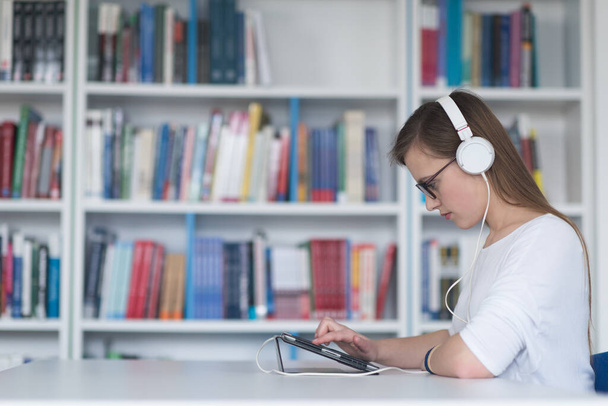 Estudante do sexo feminino estuda em biblioteca, utilizando tablet e busca de informações na internet - Foto, Imagem